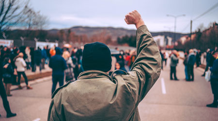 a view of the back of a man with fist raised at a protest